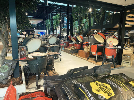 Een winkelinterieur met kamado barbecues, groene planten en een lantaarnpaal.