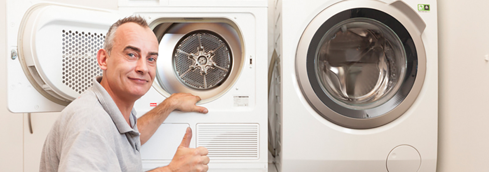 Man wijst glimlachend naar een open wasmachine of droger en steekt zijn duim omhoog.