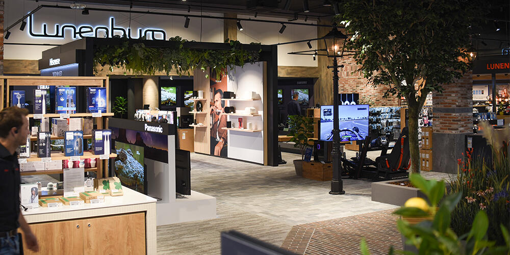 Winkelinterieur met elektronica en decoratieve elementen zoals planten en displayverlichting.