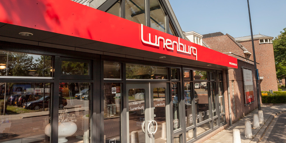 Pand met een rode luifel waarop "Lunenburg" staat, en glazen voorgevel met deuren.