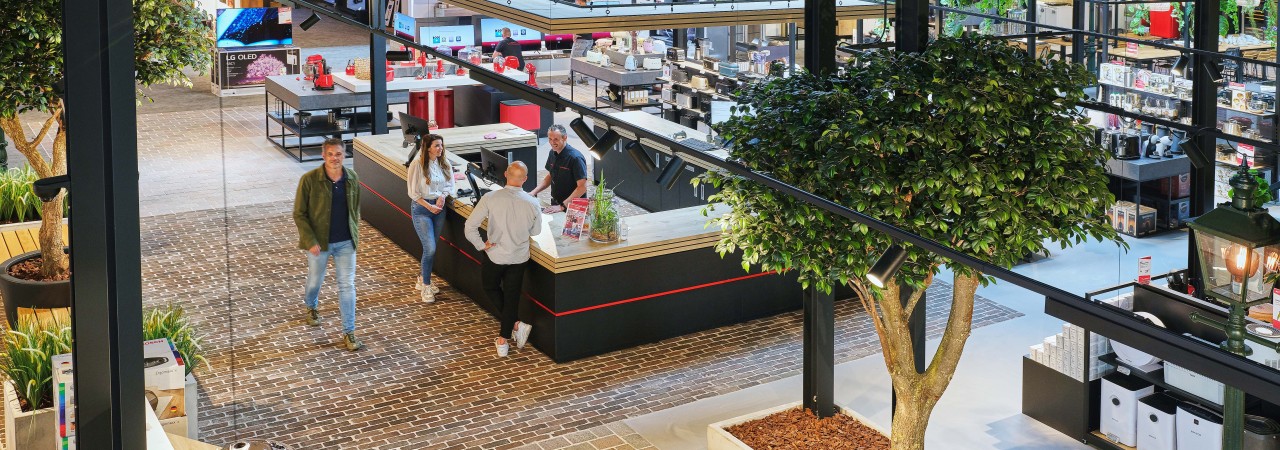 Een moderne winkel met klanten bij een centraal gelegen informatie- of servicebalie.