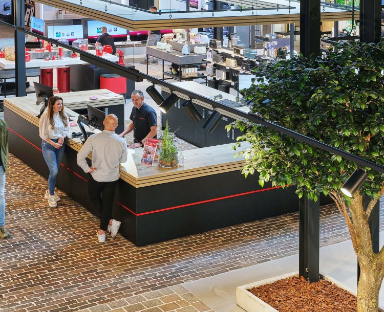 Een moderne winkel met klanten bij een centraal gelegen informatie- of servicebalie.