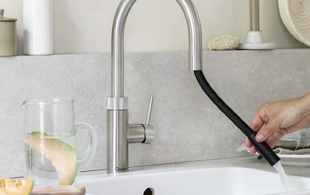 Keuken met moderne kraan waar water uit stroomt en een hand die de kraan vasthoudt.