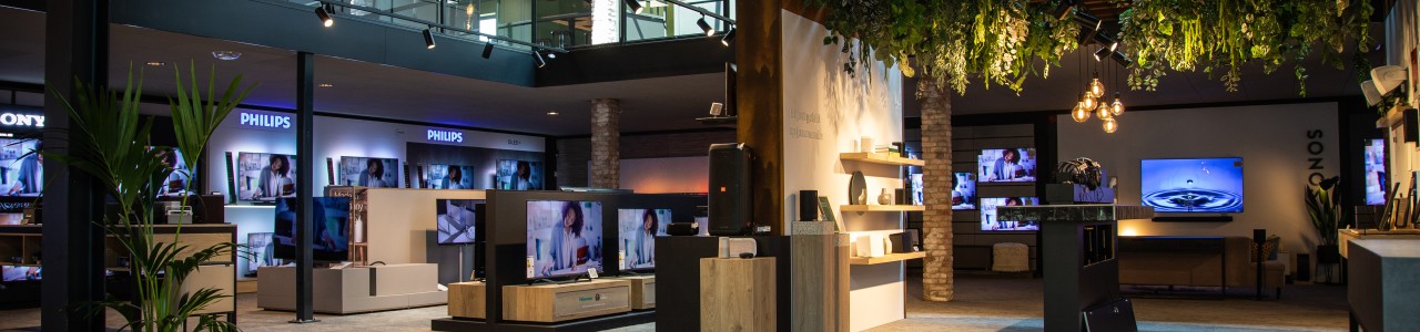 Winkel met televisies, elektronica en decoratieve planten aan het plafond.