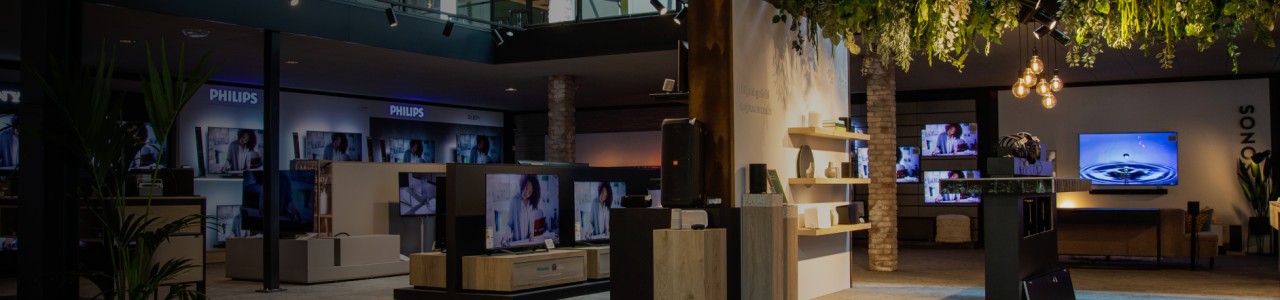 Een moderne elektronica winkel met televisies en planten aan het plafond.