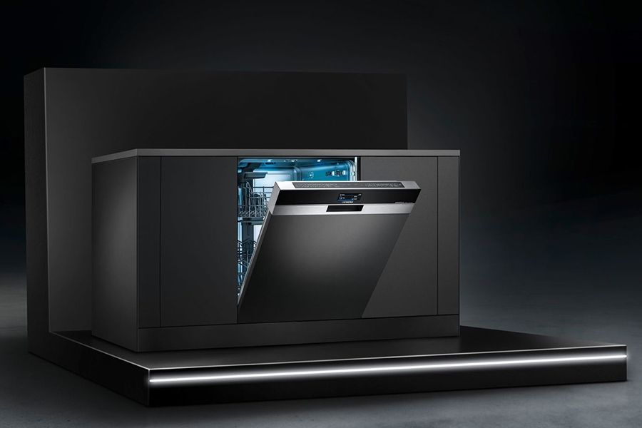 Open moderne vaatwasser in een donkere keukenomgeving.