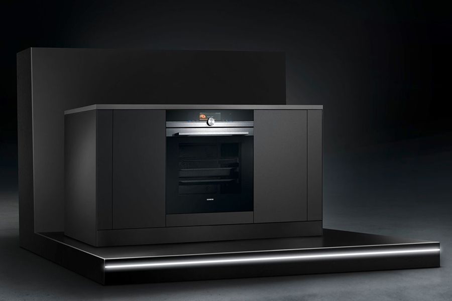 Een moderne, zwarte oven ingebouwd in een minimalistisch keukenkastje.