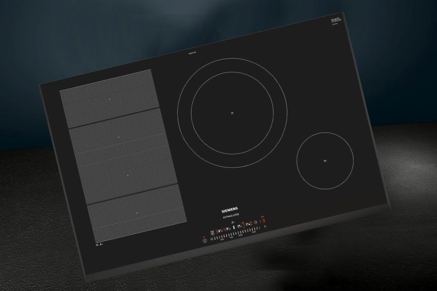 Zwarte inductiekookplaat met verschillende kookzones en bedieningspaneel aan de voorkant.