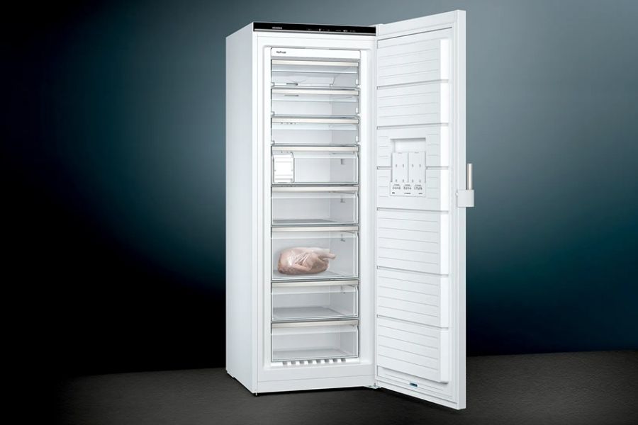 Een openstaande witte vriezer met meerdere lades, waarvan één lade een verpakte kalkoen bevat.