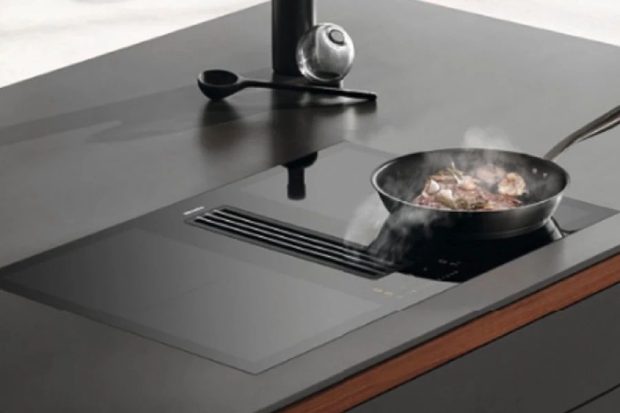 Inductiekookplaat met geïntegreerde afzuiging, met een pan waarin eten wordt gekookt.