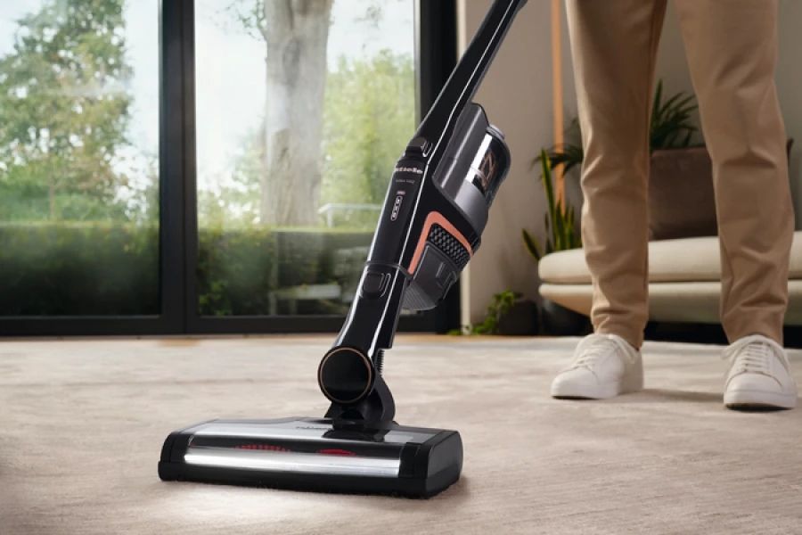 Persoon die een moderne stofzuiger gebruikt op een tapijt in een woonkamer