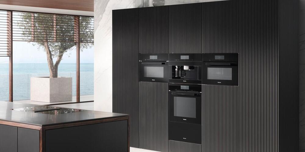 Moderne keuken met ingebouwde apparaten, grote ramen en uitzicht op zee.