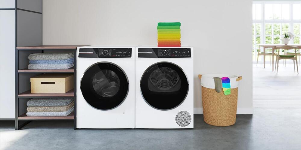 Wasmachine en droger naast elkaar, met gevouwen handdoeken, mand en een tafel in de achtergrond.