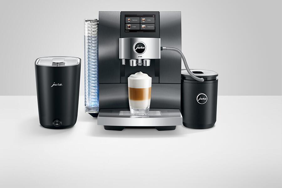 Koffiemachine met melkopschuimer en glas met koffie en melkschuim op tafel.